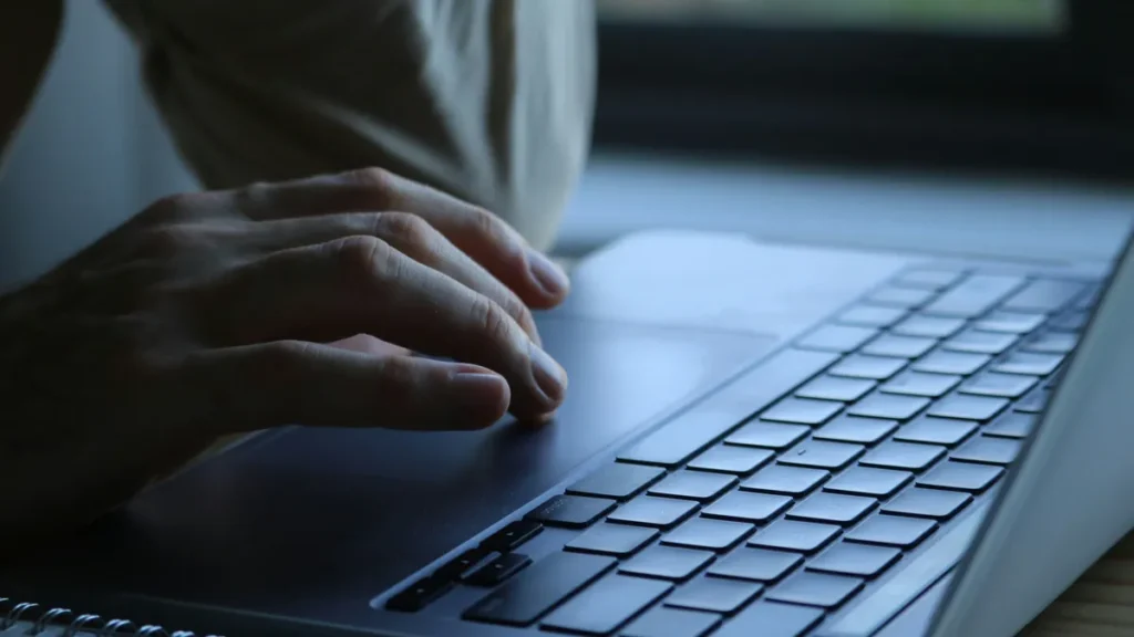 Hands typing a message on a laptop keyboard in soft light