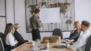 Executive presenting a growth chart to colleagues around a conference room table
