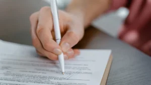 Hand signing a licensing agreement with a pen, the kind of contract that sets royalty terms