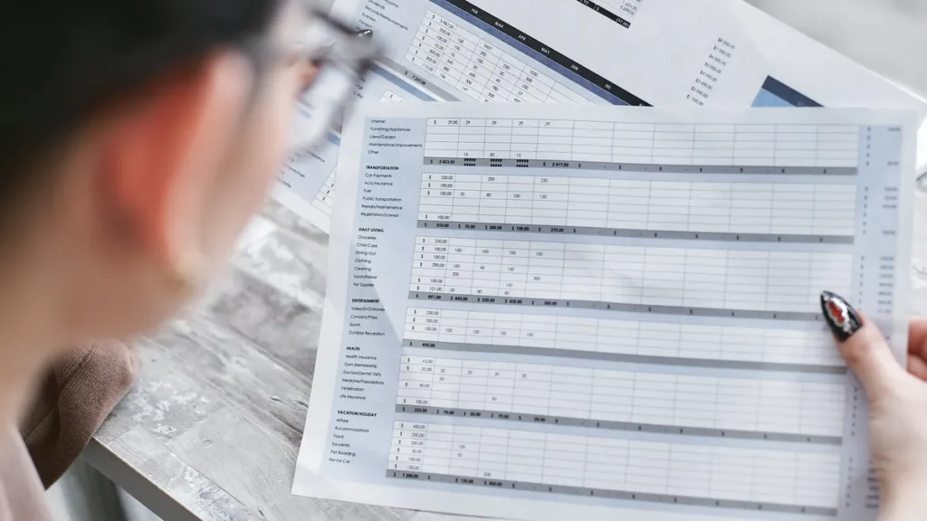 Person reviewing a printed financial statement with rows of figures and charts